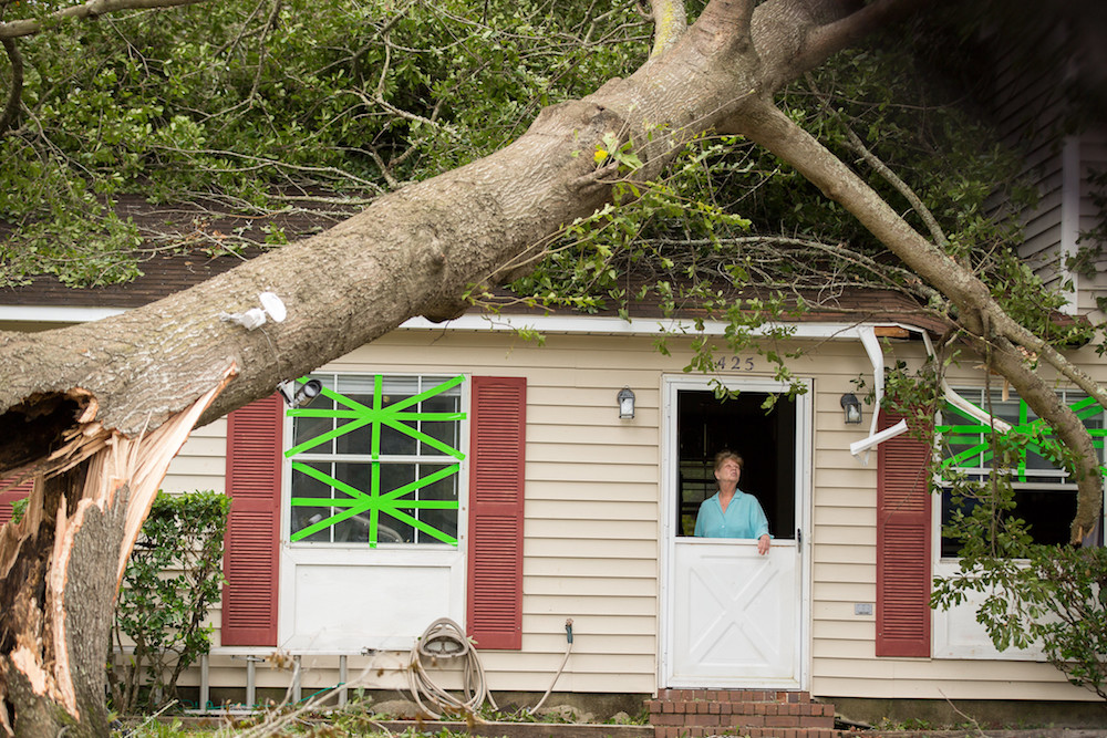 Woman in a house under a downed tree from Hurricane Matthew