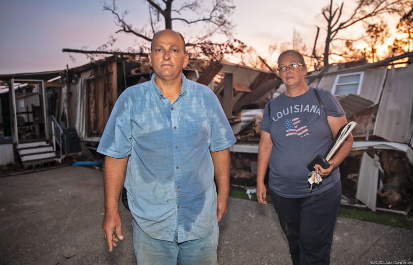 A couple stands in front of their destroyed home after Hurricane Laura