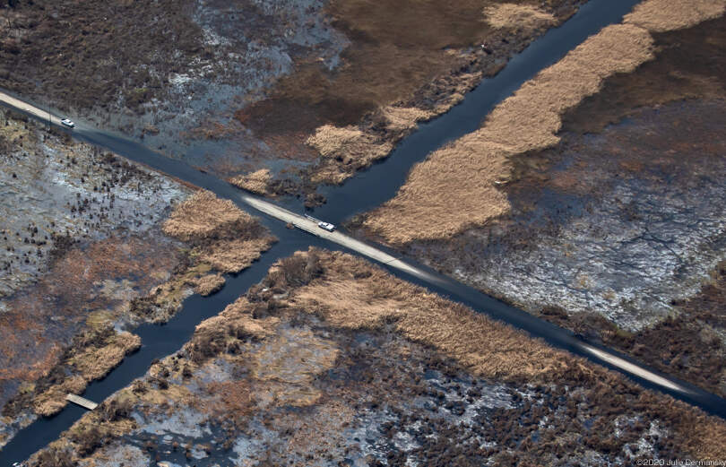 Flooded road in Cameron Parish after Hurricane Laura, surrounded by oiled wetlands