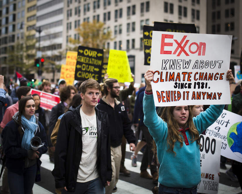 Protesters with signs saying 'Exxon knew about climate change since 1981. Denied it anyway.'