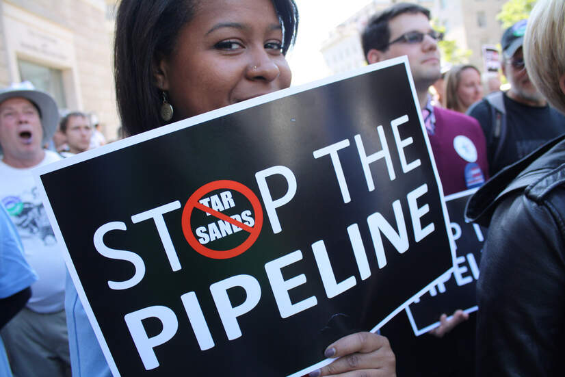 A woman holds a 'Stop the tar sands pipeline' sign at a Keystone XL protest rally in 2011.